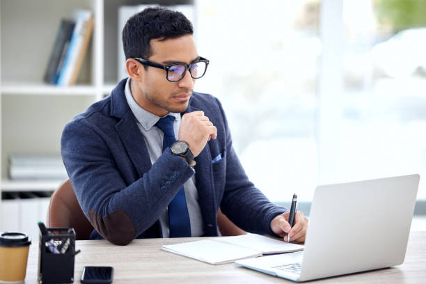 istock Shot of a businessman making notes while using his laptop 1370784747