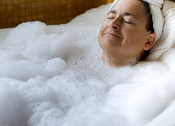 istock Woman with towel on head soaking in a foamy bath 137078630