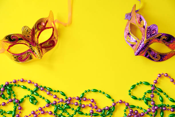 istock Two multi-colored carnival masks and beads on yellow background. Mardi Gras concept. Fat Tuesday symbol. 1370793507
