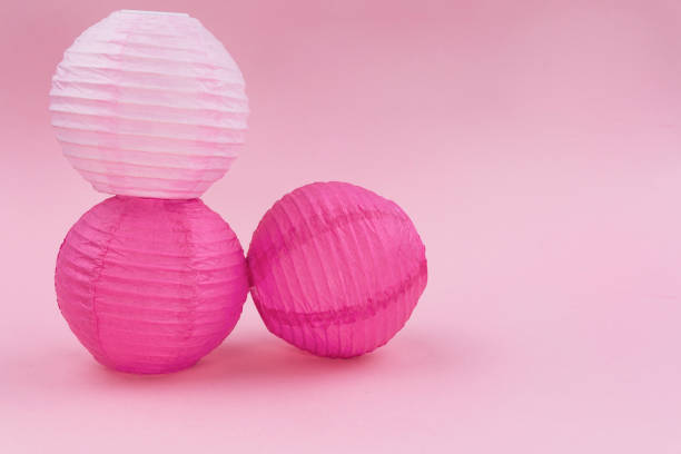 three spheres in different shades of paper on pink background