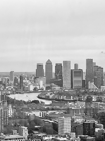 An aerial monochrome shot of the River Thames with a skyline of the modern buildings of London’s Docklands.