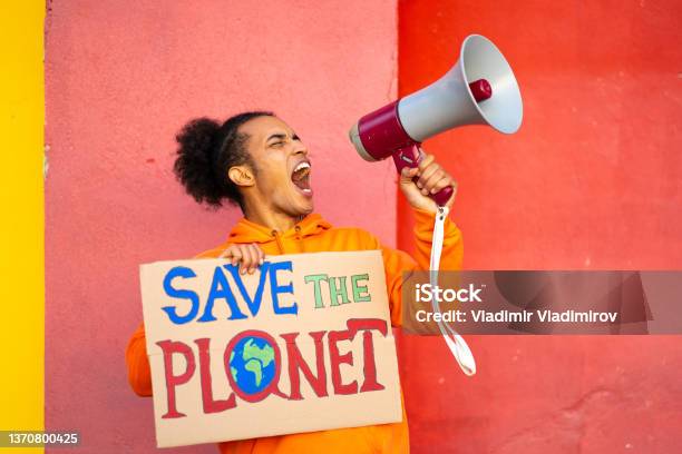 Protesting Using Megaphone Against An Orange Striped Wall Stock Photo - Download Image Now