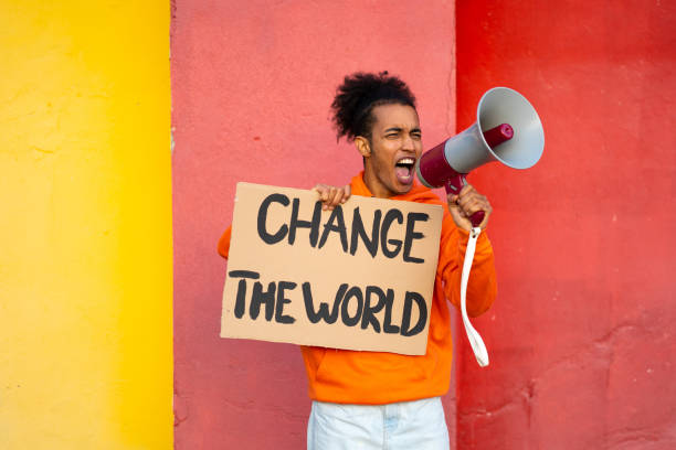 Male activist using a megaphone A young African-American man is holding a placard in one hand with a Change message while shouting through the megaphone he has in his other hand cool climate stock pictures, royalty-free photos & images