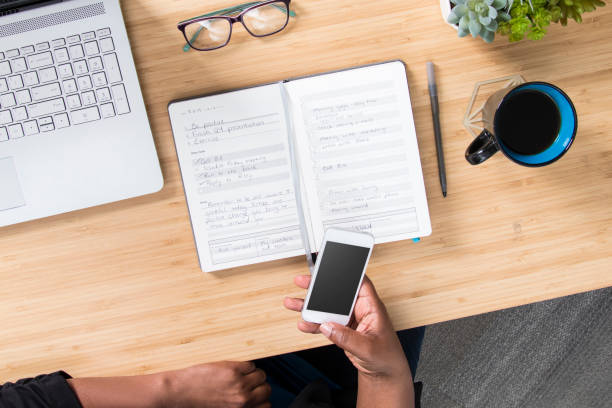 istock Woman using notebook planner in office on desk with cellphone and computer 1370806047