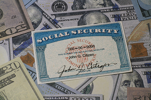 Lake Elsinore, CA, USA - January 30, 2022: Fake Social security card on prop US currency - Concept of Social Security Benefits