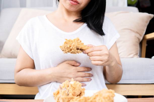 アジア人女性は唐揚げを食べ過ぎ、腹痛、食べ過ぎによる消化不良、過食症 - chicken tender ストックフォトと画像