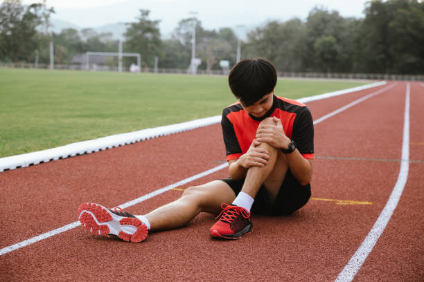 le jeune coureur a une blessure au genou. causée par des chutes, des crampes sur la piste d’athlétisme. - cramping photos et images de collection