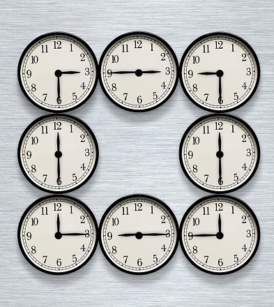 Close-up of lined up clocks from 9 to 5 on white background.
