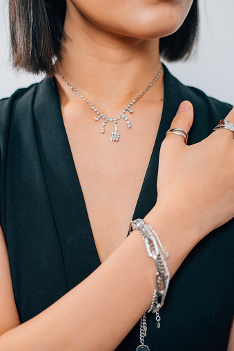 Portrait beautiful An Asian woman with jewelry. Brunette girl with short black smooth hair.  Close-up of an Asian woman with luxury accessories such as diamond ring, necklace and silver bracelet with white background.