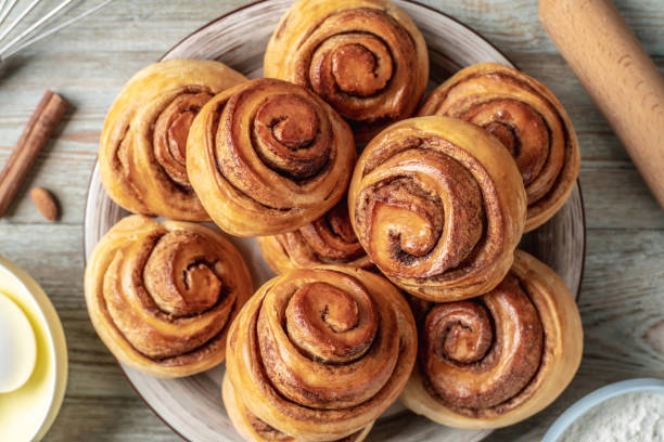 istock There is a plate with homemade fresh delicious cinnamon rolls, ingredients for their preparation and kitchen tools on the wooden table . Top view 1370831214
