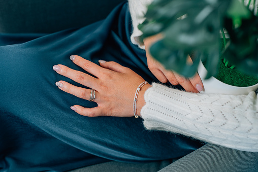 Young woman hand with rings and bracelet holding a flower pot.