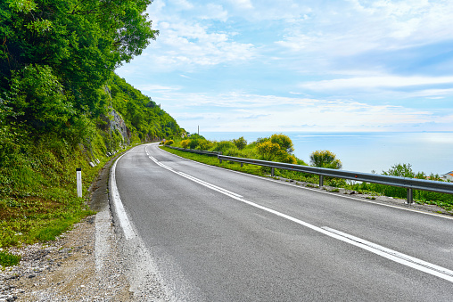 A beautiful road along the sea with steep cliffs. View of the blue sky and the sea. Montenegro