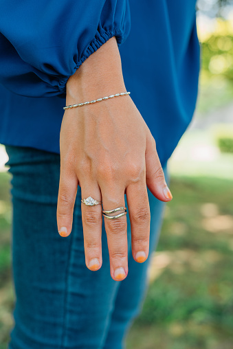 Fashionable women's accessories. Detail of the body of a model dressed in light blue jeans. Jewelry from diamond ring and bracelet outdoor.