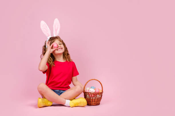 イースターバニーの耳の女の子は床に座って、卵で目を覆う - easter egg 写真 ストックフォトと画像