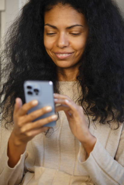 istock Happy black woman browsing internet on mobile phone. Cheerful African female using modern blue smartphone with triple camera. Young adult person communicating online with new cellphone gadget 1370839875