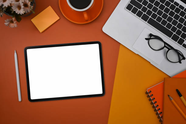 istock Digital tablet, stylus pen, laptop computer and notebook on orange background. 1370840102