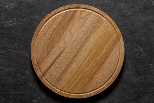 istock Round wooden pizza stand board, top view dark background, with space to copy text.