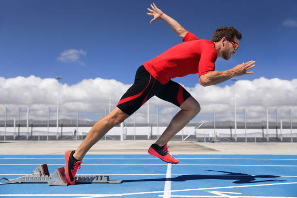 atleta corredor começando a correr no início da pista de corrida em pistas azuis de corrida no atletismo ao ar livre e no estádio fiel. velocista. homem do esporte e fitness correndo correndo. - starting line sprinting track and field track event - fotografias e filmes do acervo