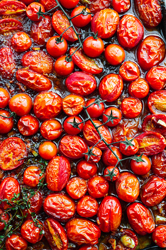 Roasted cherry and rosa tomatoes viewed from above on a baking sheet.