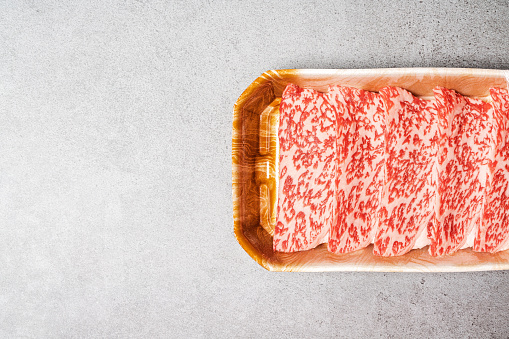 Premium Rare Slices sirloin Wagyu A5 beef with high-marbling texture on food tray served for Yakiniku, Sukiyaki and Shabu. Place on background with copy space.