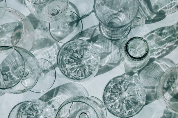 istock Beautiful different glasses stand on white background in sunlight and create shadows. Hard light, long shadows. Creative concept of drinks, alcohol cocktails. Glassware concept 1370843830