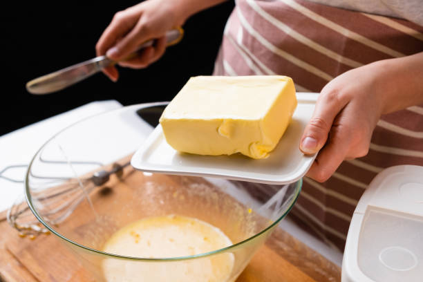 istock The dough preparation process. Female hands add butter into the mixing bowl for baking cake on a black background. Homemade recipe of pastry 1370845210