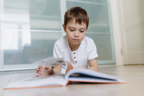 istock A boy reading a book on the floor at home. Image with selective focus 1370845969
