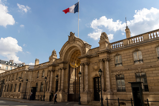 Paris, France - June 17, 2021: Facade of the Elysée Palace official residence of the President of the French Republic rue Saint Honoré in Paris in good weather with French flag flying in the wind,