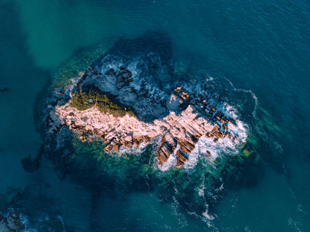 Aerial view of the picturesque scene of sea waves crashing on the cliff. Lonely rocky island in windy weather at high tide Aerial view of the picturesque scene of sea waves crashing on the cliff. Lonely rocky island in windy weather at high tide halkidiki beach stock pictures, royalty-free photos & images