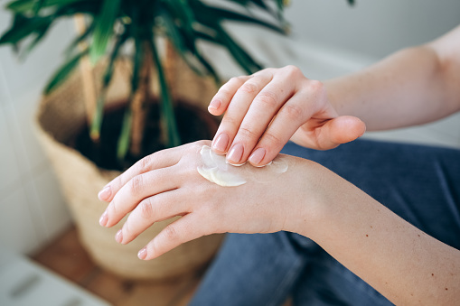 Mujer unta una crema de manos hidratante en la piel de la mano photo