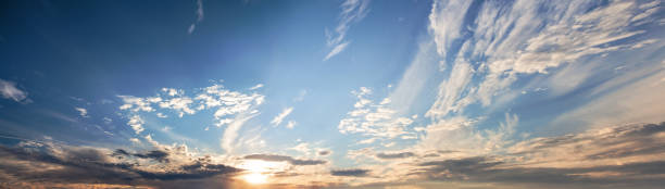 istock Spring landscape with white clouds and orange sun on sky 1370850605