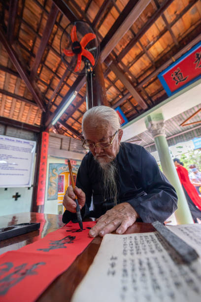 Vietnamese scholar writes calligraphy at lunar new year. Calligraphy festival is a popular tradition during Tet holiday. Culture of Vietnamese Tet stock photo