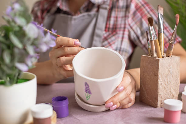 istock Women in gray apron paint a white flower ceramic pot 1370855042