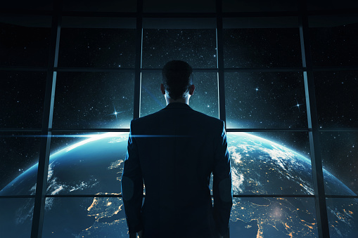 Abstract image of young, successful businessman looking at the planet earth at night