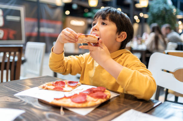 kind isst eine pizza - ein junge allein stock-fotos und bilder