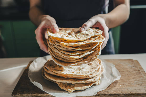 frisch gebackenes fladenbrot in den händen des kochs - gericht des mittleren ostens stock-fotos und bilder