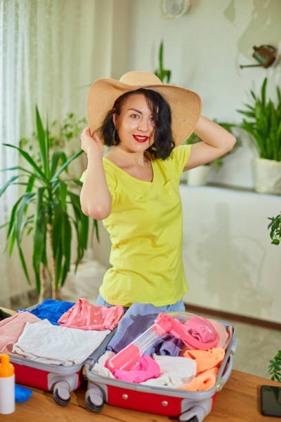 istock Happy woman in hat dancing, packing suitcase, getting ready for summer vacation 1370857609