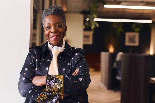 retrato de mulher negra sênior confiante sorrindo e olhando para a câmera com os braços cruzados - leadership business women senior adult - fotografias e filmes do acervo