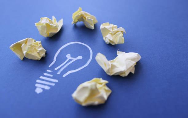 istock Lot of crumpled papers lying on drawn light bulb closeup 1370861807