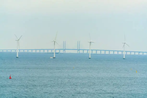 The Øresund Bridge that connects Denmark and Sweden via Malmø and Copenhagen. With ocean wind turbines in the front.