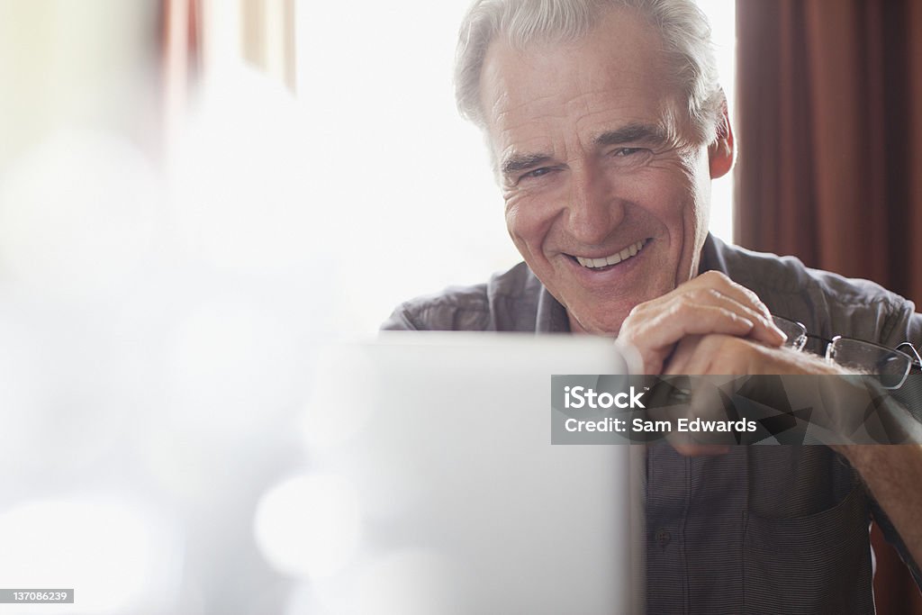 Retrato de homem senior sorridente segurando óculos e utilizar lapt - Royalty-free E-mail Foto de stock