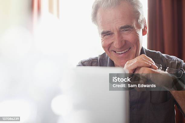 Retrato De Homem Senior Sorridente Segurando Óculos E Utilizar Lapt - Fotografias de stock e mais imagens de E-mail