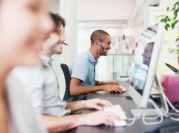 Photo of Business people with headsets working at computers in office