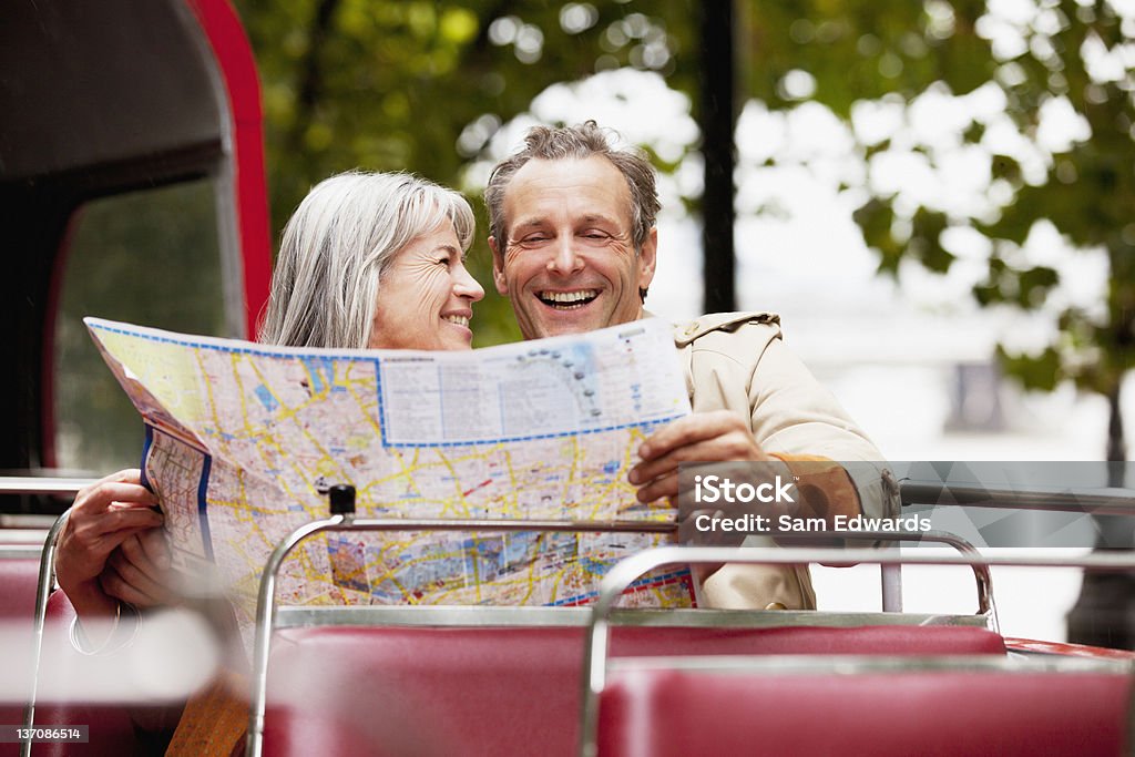 Coppia sorridente guardando la mappa su autobus a due piani - Foto stock royalty-free di Adulto in età matura