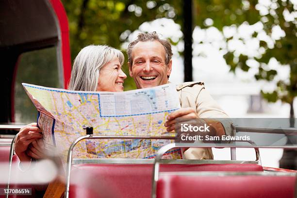 Coppia Sorridente Guardando La Mappa Su Autobus A Due Piani - Fotografie stock e altre immagini di Adulto in età matura