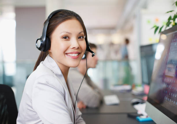 retrato de mulher de negócios sorridente com fone de ouvido no computador em - women customer service representative people sales occupation - fotografias e filmes do acervo