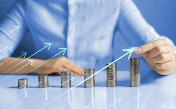istock Hand putting money coin stack with growing business graph.Saving money concept. 1370867514
