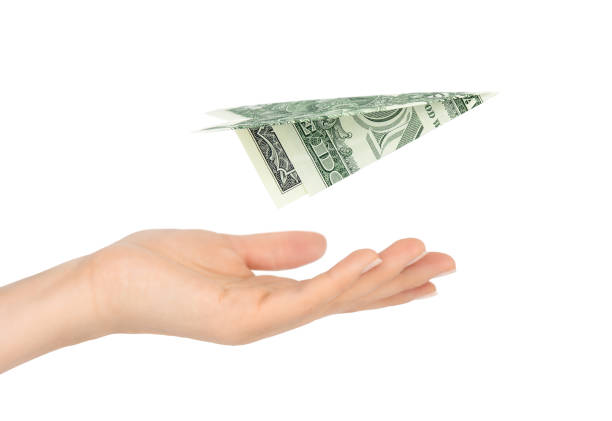 Dollar bill plane above female hand isolated on white background One dollar bill origami plane above female hand isolated on white background making money origami stock pictures, royalty-free photos & images