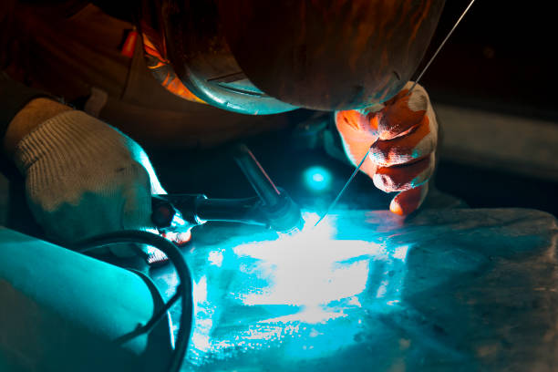The welder ignites the arc and begins welding the aluminum canister with argon arc welding.