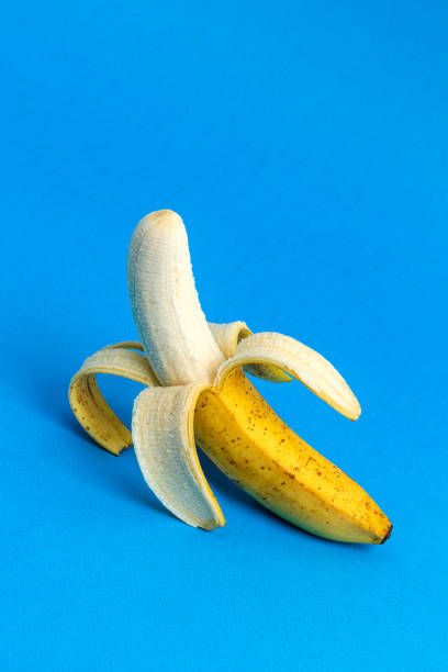 istock Peeled banana on blue background. Copy space. 1370870533